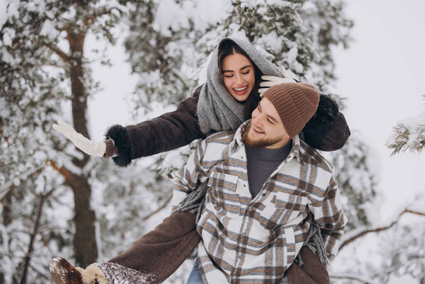 Młoda szczęśliwa i kochająca się para bawi się w śnieżnym lesie zimą. - Zdjęcie, obraz
