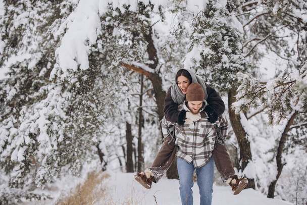 Una joven pareja feliz y cariñosa se divierte en un bosque nevado en invierno. - Foto, Imagen