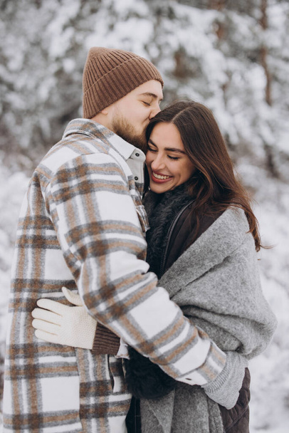 Una joven pareja feliz y cariñosa caminando en un bosque nevado de invierno en las montañas - Foto, Imagen