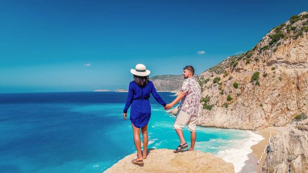 休暇中のカプタスビーチカス・トルコ,夏の間にカス・トルコ海の崖から白いオレンジ色のビーチ,夏休み中に崖の上に立っている男性と女性 - 写真・画像
