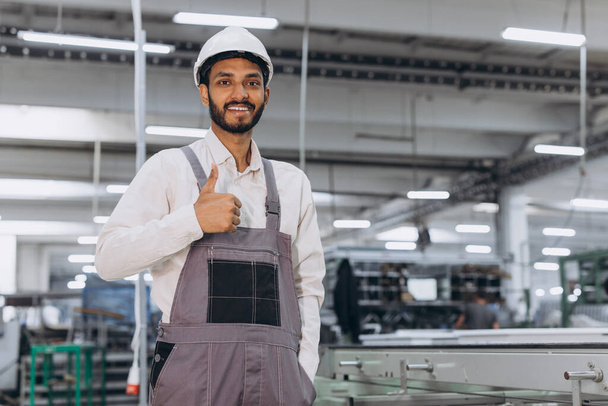 Bediener der Maschine. Internationaler indischer Industriearbeiter in einer Fabrik. Junger Techniker mit weißem Hut. - Foto, Bild