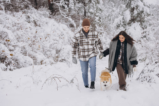 Щаслива молода пара з собакою Акітою в лісі взимку і сніжний день - Фото, зображення