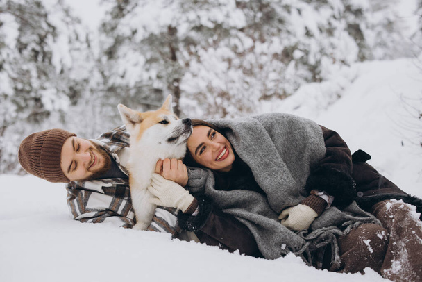 Gelukkig jong stel met akita hond in het bos op winterdag - Foto, afbeelding
