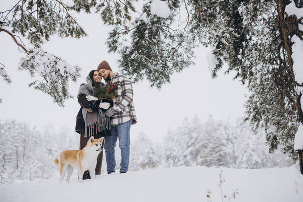 Šťastný mladý pár s akita pes v lese v zimní den - Fotografie, Obrázek