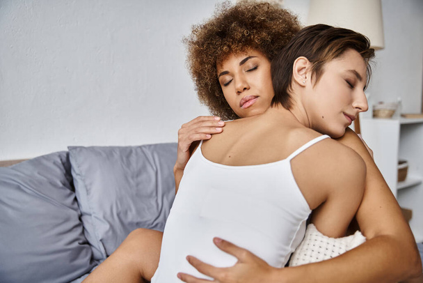 iloinen monikulttuurinen lesbo nuori pari suljetuin silmin halaavat toisiaan makuuhuoneessa - Valokuva, kuva