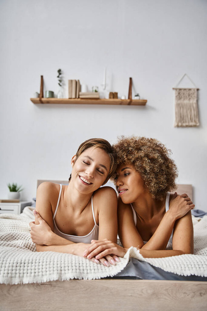 feliz interracial lésbicas parceiros desfrutando manhã enquanto deitado juntos na cama em casa, aconchegante - Foto, Imagem