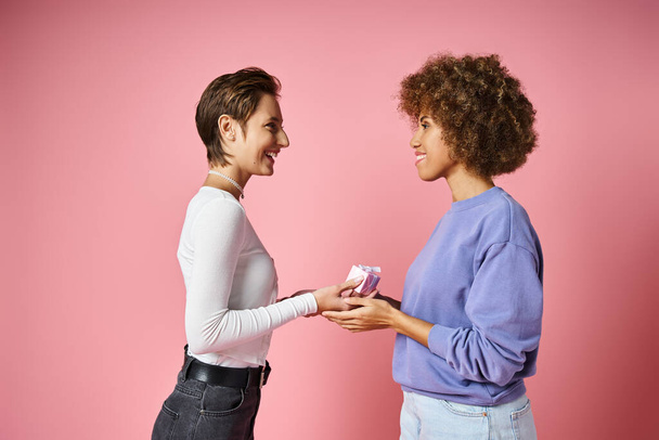 allegra donna lesbica dando regalo a felice ragazza afro-americana il giorno di San Valentino - Foto, immagini