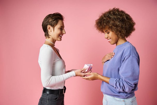 allegra donna lesbica dando regalo alla gioiosa fidanzata afro-americana il giorno di San Valentino - Foto, immagini