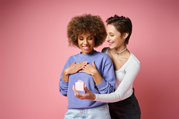 cheerful lesbian woman giving present to amazed african american girlfriend on Valentins day - Photo, Image