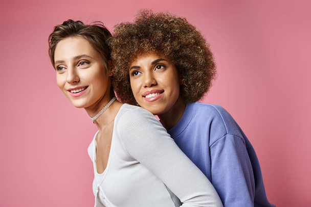 щаслива афроамериканка позує зі своєю дівчиною на рожевому фоні, lgbtq пара кохання - Фото, зображення