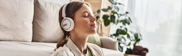 carefree teenage girl in her wireless headphones listening music and holding cup of tea, banner - Foto, afbeelding