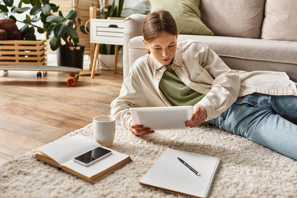 teenage girl holding tablet near cup of tea while making her homework, digital native concept - Foto, Imagem