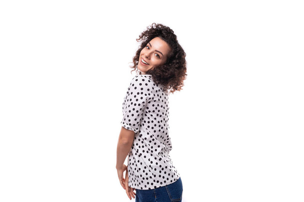 junge gepflegte brünette lockige Frau in einer Bluse mit Erbsenmuster gekleidet. - Foto, Bild