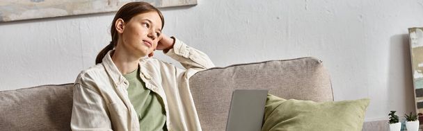 banner of dreamy teenage girl sitting with her laptop on a sofa at home, e-learning concept - Photo, Image