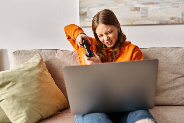 angespannte Teenager-Mädchen spielen Spiel mit Steuerknüppel und Laptop und sitzen auf dem Sofa zu Hause, Unterhaltung - Foto, Bild