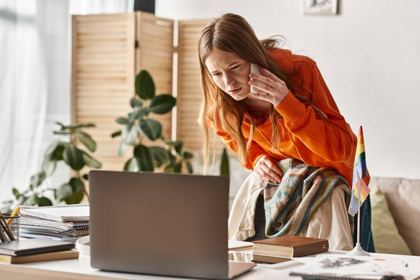 soustředěný teenager dívka studující on-line doma, dělat hovor vedle pýchy Igbtq vlajka na stole - Fotografie, Obrázek