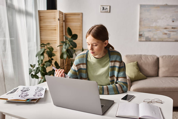 Focused teen girl e-learning z laptopem w pobliżu rysunków i smartfonem z czystym ekranem na biurku - Zdjęcie, obraz