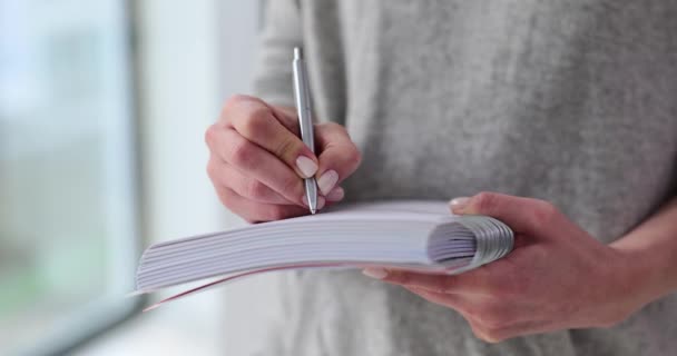 Γυναίκα στέκεται κρατώντας στυλό και γράφοντας στο ημερολόγιο closeup. Επιχειρηματίας γράφει τις επιχειρηματικές ιδέες και τα σχέδια εκκίνησης και δημιουργικές σκέψεις στο σημειωματάριο - Πλάνα, βίντεο