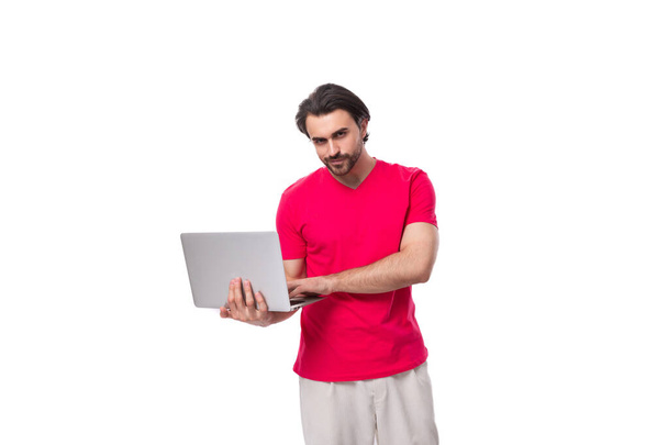 joven especialista en TI masculino sosteniendo un ordenador portátil en sus manos sobre un fondo blanco con espacio para copiar. - Foto, imagen
