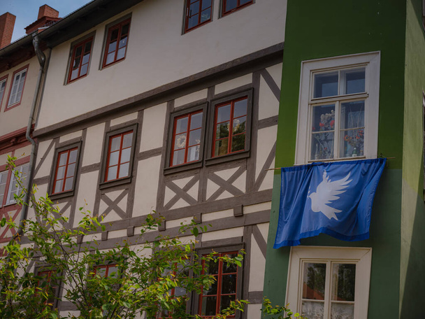 kevätmatka Eurooppaan. luonnonkaunis näkymä julkisivu vanhoja historiallisia taloja jonnekin Erfurt kaupunki, sininen lippu kyyhkynen rauhan että asukkaat talon ripustettu niiden julkisivu - Valokuva, kuva