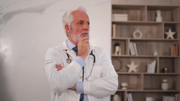 Sad tired mature senior male doctor in medical uniform in hospital or doctor office. Unhappy General Practitioner GP therapist professional healthcare expert in clinic. Healthcare concept - Footage, Video