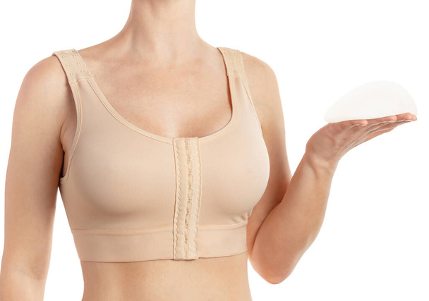 Женщина в компрессионном бюстгальтере, с анатомическим грудным имплантатом на белом фоне.  - Фото, изображение