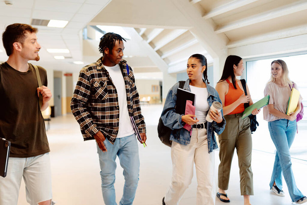 mutiracial group of girls and boys walking together in the halls of the university or high school. Students from different cultures together at school - Photo, Image