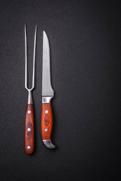 Coltello da cucina e forchetta in acciaio con spazio copia su uno sfondo di cemento scuro - Foto, immagini