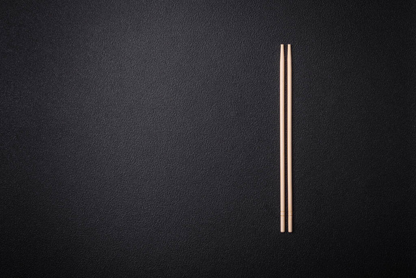 Bílé dřevěné hůlky pro asijské pokrmy s kopírovacím prostorem na tmavém betonovém pozadí - Fotografie, Obrázek