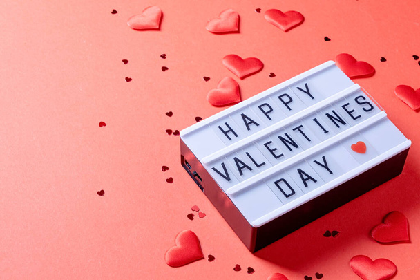 Sevgililer Günü. Üzerinde "Sevgililer Günün kutlu olsun" yazan bir mektup tahtası. Kırmızı arka planda kalp şeklinde bir konfeti. - Fotoğraf, Görsel