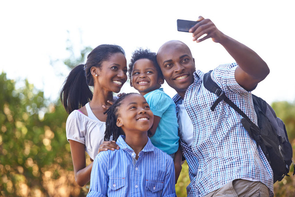 Onnellinen musta perhe, selfie ja valokuva luonnossa patikointiin, liimaukseen tai ulkokuvaukseen yhdessä. Afrikkalainen äiti, lapset ja isä hymy ottaa kuvan tai valokuvan seikkailu metsässä. - Valokuva, kuva