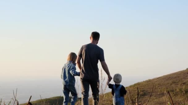 Ο πατέρας περπατάει με παιδιά. Χαρούμενη οικογενειακή βόλτα στο ηλιοβασίλεμα στη φύση. . Υψηλής ποιότητας 4k πλάνα - Πλάνα, βίντεο