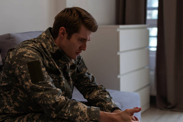 Hombre nervioso militar sufriendo depresión, sentado solo en casa, concepto PTSD
 - Foto, Imagen