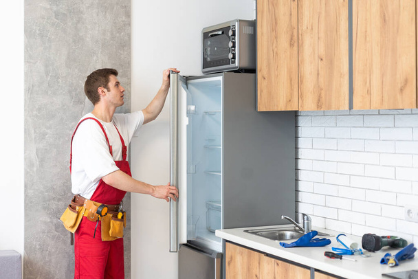 Munkás javítás hűtőszekrény a konyhában. - Fotó, kép