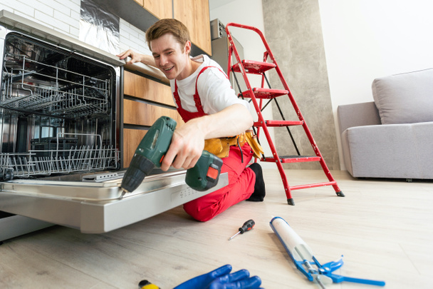 Master of Maintenance: Jonge man die reparatiediensten voor huishoudelijke apparaten aanbiedt. - Foto, afbeelding