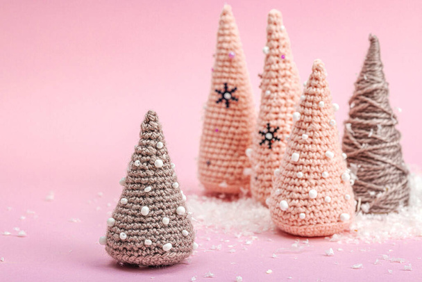 Composizione invernale fatta a mano. Set di alberi di Natale all'uncinetto, neve artificiale su sfondo rosa. Creativo concetto di hobby, vista dall'alto - Foto, immagini