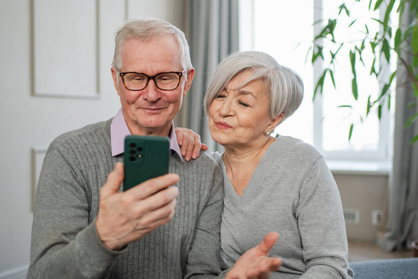 Video call. Happy senior couple woman man with smartphone having video call. Mature old grandmother grandfather talking speaking online. Older generation modern tech usage. Virtual meeting online chat - Photo, Image