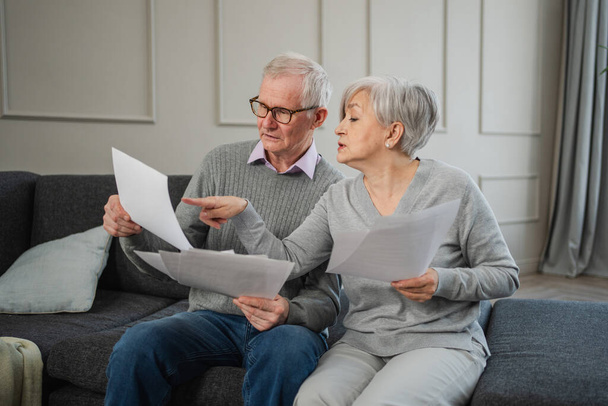 Szomorú, hogy a középkorú idős házaspár papírral ül. Boldogtalan idősebb férfi nő olvasás papír számla kezelése banki pénzügyek kiszámítása adók tervezés hitel adósság nyugdíjkifizetés - Fotó, kép