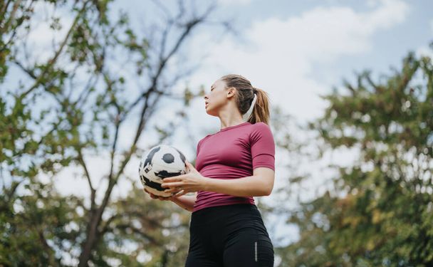 Спортсмен тренується на відкритому повітрі, насолоджуючись природним середовищем. Вона демонструє свою форму тіла з футбольними трюками, жонглюючи футбольний м'яч. - Фото, зображення