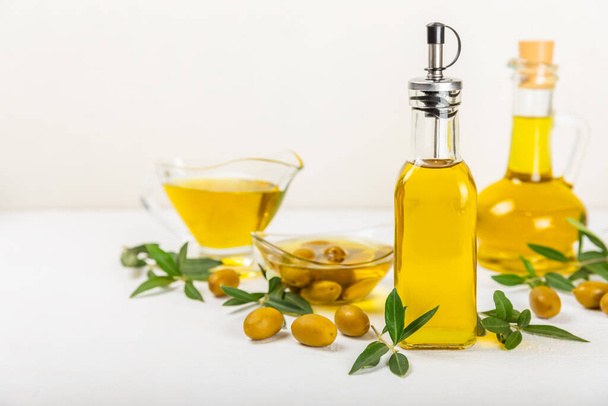 Olive oil in a bottle on a white texture background. Oil bottle with branches and fruits of olives. Place for text. copy space. cooking oil and salad dressing. - Photo, Image