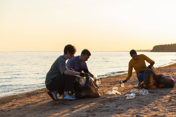 Maan päivä. Vapaaehtoiset aktivistit keräävät roskien puhdistusta rantaviivasta. Nainen ja mies laittavat muovijätettä roskapussiin meren rannalla. Ympäristönsuojelu rannikkoalueiden puhdistus - Valokuva, kuva
