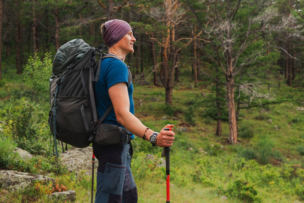 ハイキング観光アドベンチャー。 バックパッカーのハイカーマンは美しい景色を見ています. 緑の森を歩くバックパック付きのハイカー観光客. バックビュー男性はハイキングトレッキング観光アクティブバケーションを楽しむ - 写真・画像