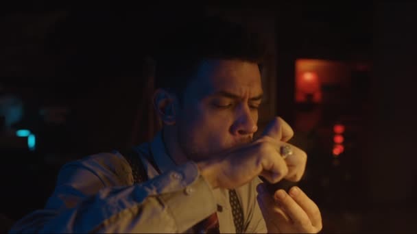 Hrudník nahoru boční záběr běloch vousatý muž v retro stylu košile a podvazky osvětlení potrubí a těší kouření v tmavé místnosti - Záběry, video