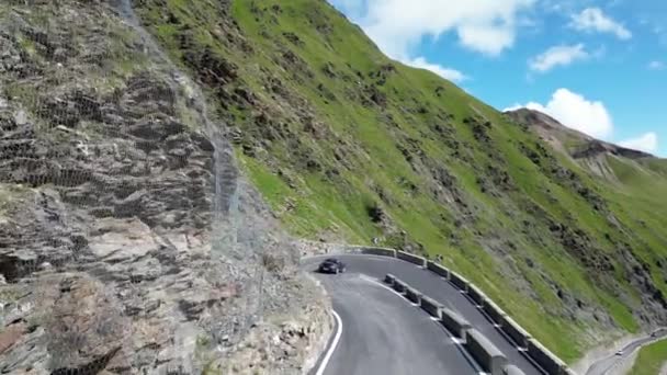 Stilfs, Italie - 30 juillet 2023 : La Porsche 911 décapotable bleue descend sur la route du col du Stelvio une serpentine avec un panorama des Alpes de montagne. La voiture est une voiture de sport fabriquée par Porsche. - Séquence, vidéo