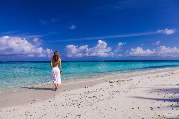 mooi meisje in witte rok en gele top op loopt het strand - Foto, afbeelding
