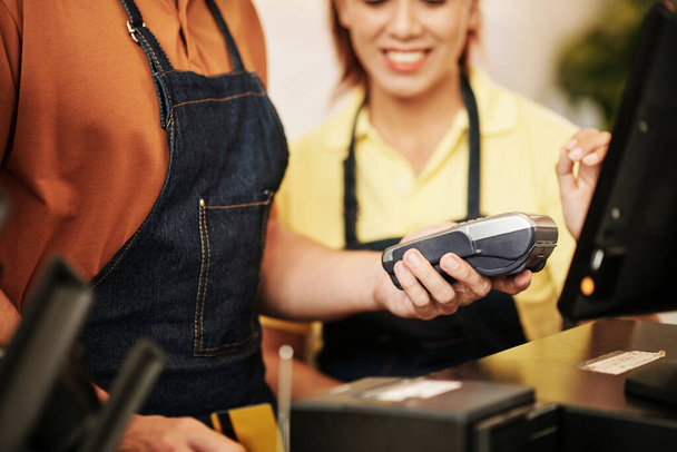 Właściciel kawiarni pokazuje nowemu pracownikowi, jak drukować pokwitowania po akceptacji płatności kartą - Zdjęcie, obraz