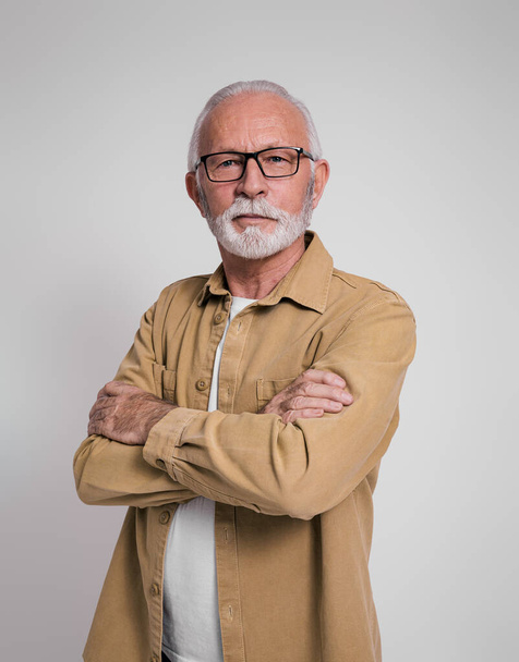 Portrét sebevědomý vousatý starší podnikatel se zkříženými pažemi stojící na bílém pozadí - Fotografie, Obrázek