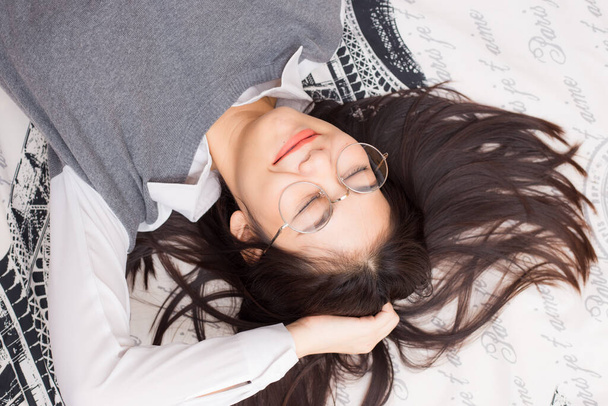 Occhiali donne rilassarsi sdraiato sul letto coperta bianca
 - Foto, immagini