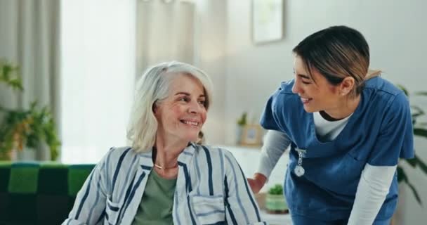 Seniorenzorg, oude vrouw in rolstoel en verpleegster met glimlach, ondersteuning en advies voor thuiszorg. Thuiszorg, bejaarde patiënt en gelukkige verzorger in de woonkamer voor overleg, hulp en vriendelijkheid - Video