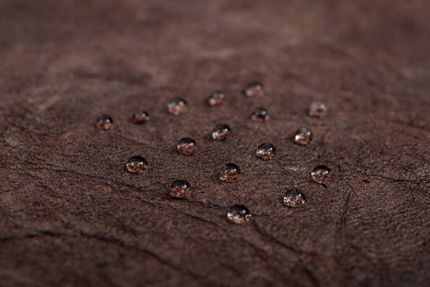 Kulaté kapky vody na tmavě hnědou koženou texturu, boční pohled, měkké ostření makro   - Fotografie, Obrázek